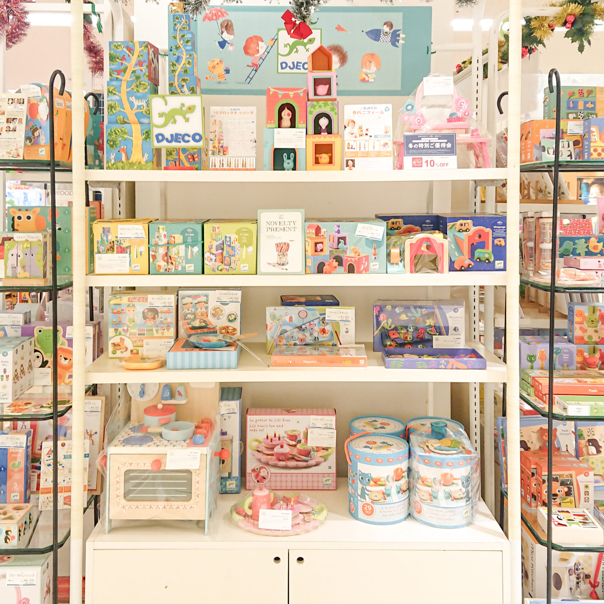 埼玉県にあるそごう大宮店のDJECOクリスマスフェアの店頭の様子です。白い棚に、おままごとや紙製積み木などのおもちゃ、黒い棚にはパズルやオルゴールなどが並んでいます。